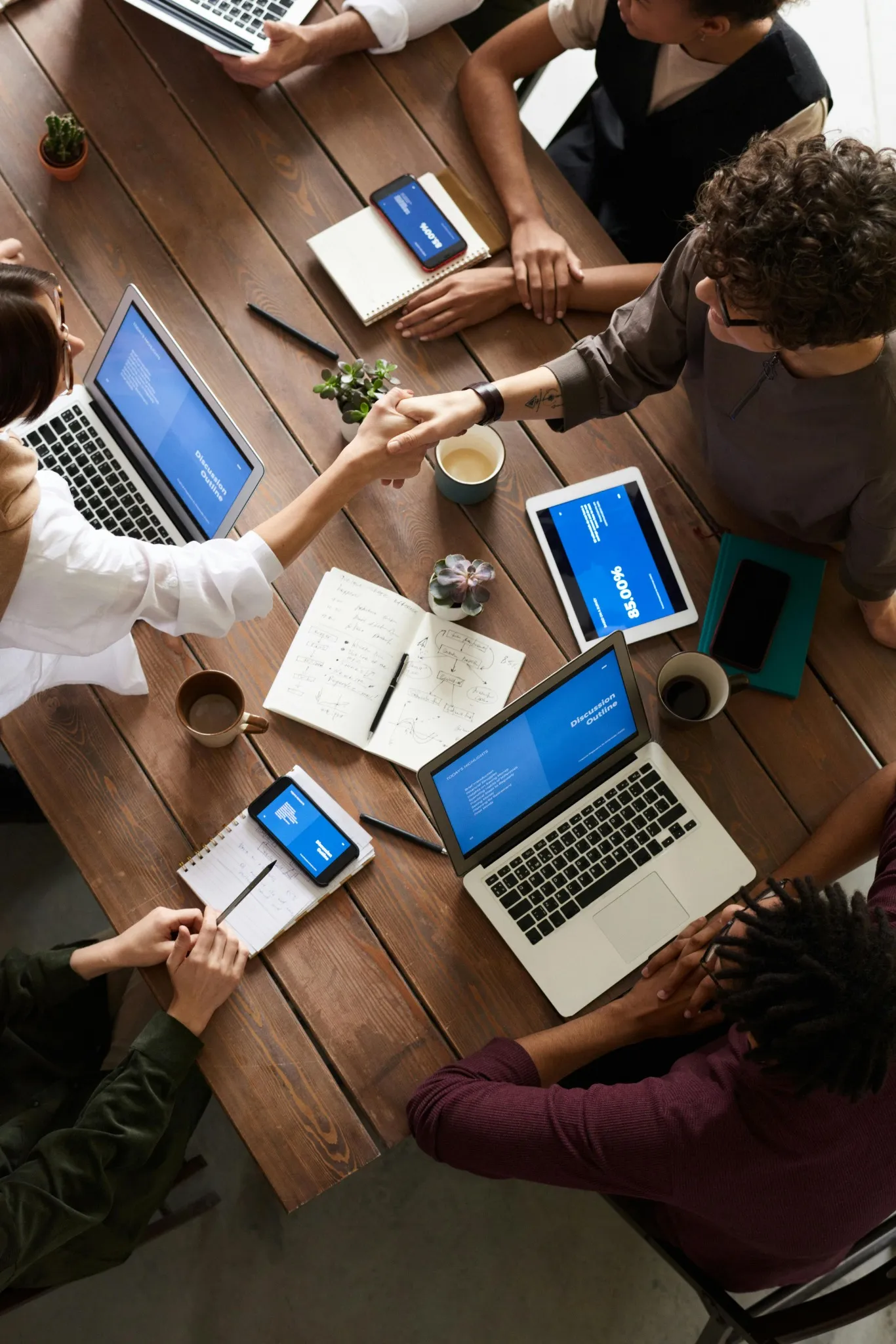 Professionals collaborating around a table with laptops and mobile devices